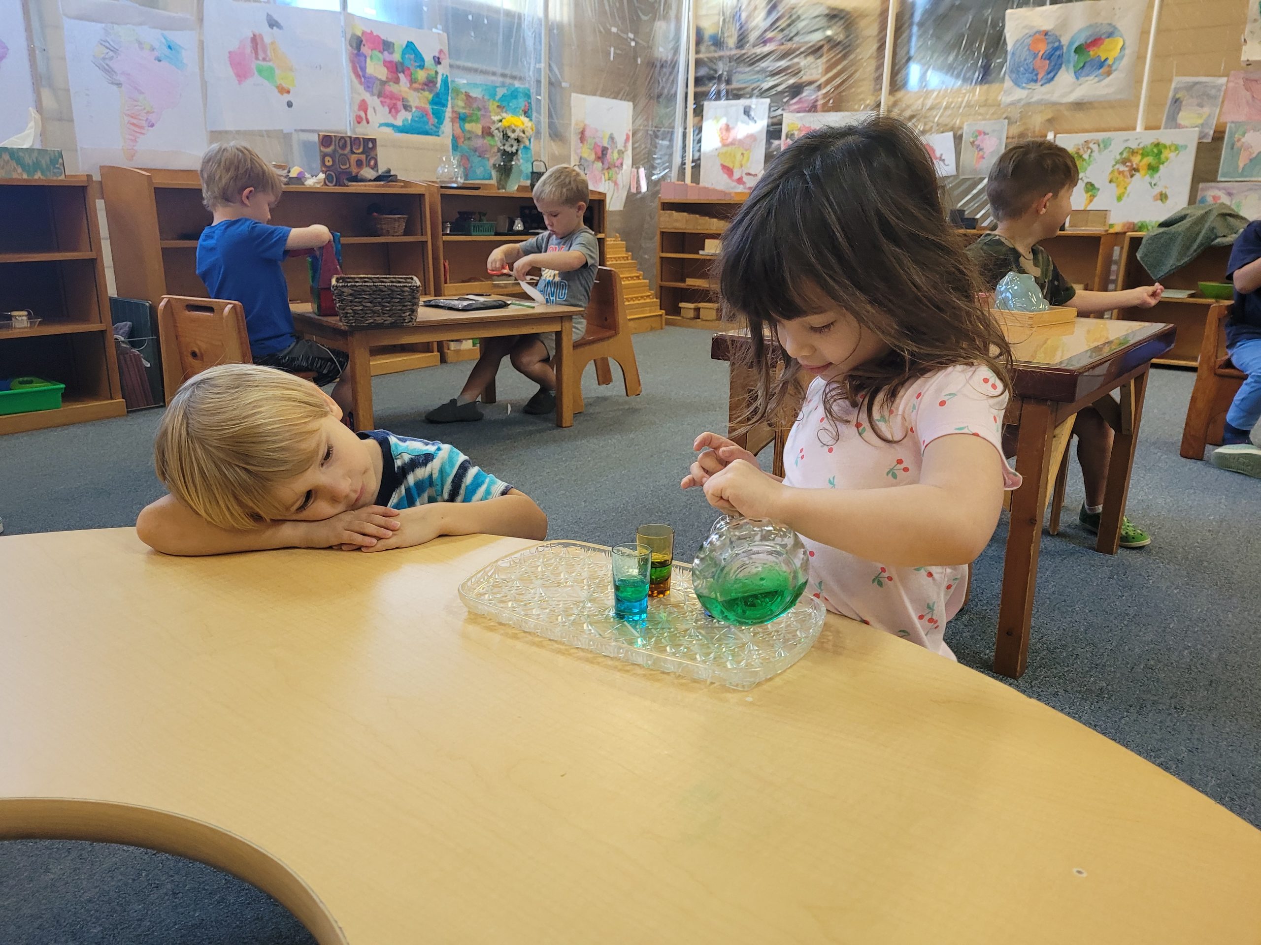 Montessori students working on water pouring activity in classroom