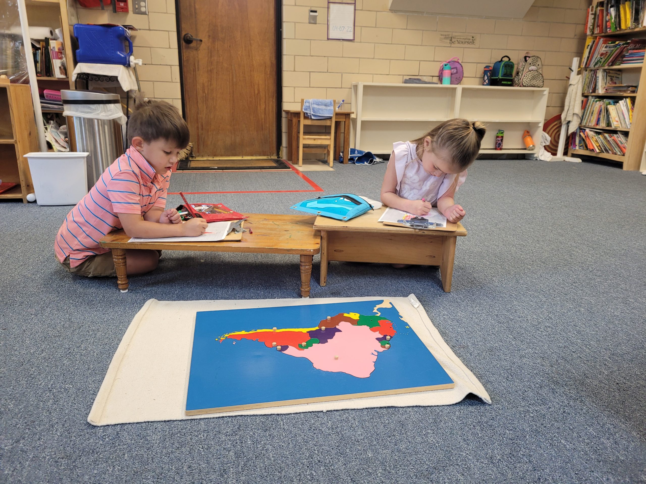Montessori students on the carpet working on a geography activity