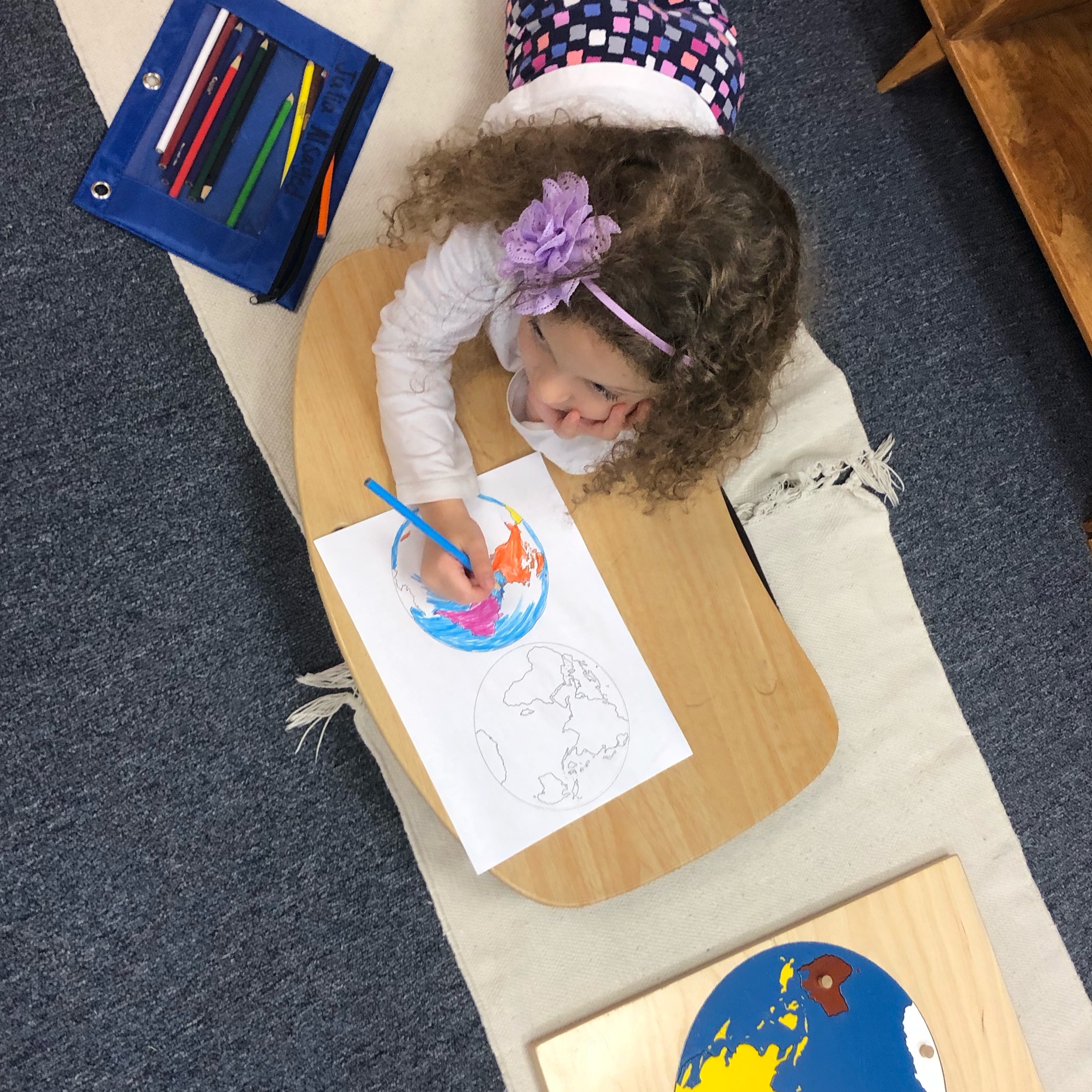 Overhead shot of Montessori student coloring a geography worksheet
