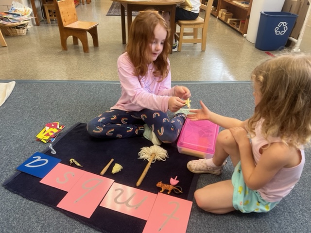Montessori students on a mat working on a sandpaper letter activity